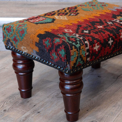 Multicoloured vintage kilim fabric patterned footstool with wooden legs 